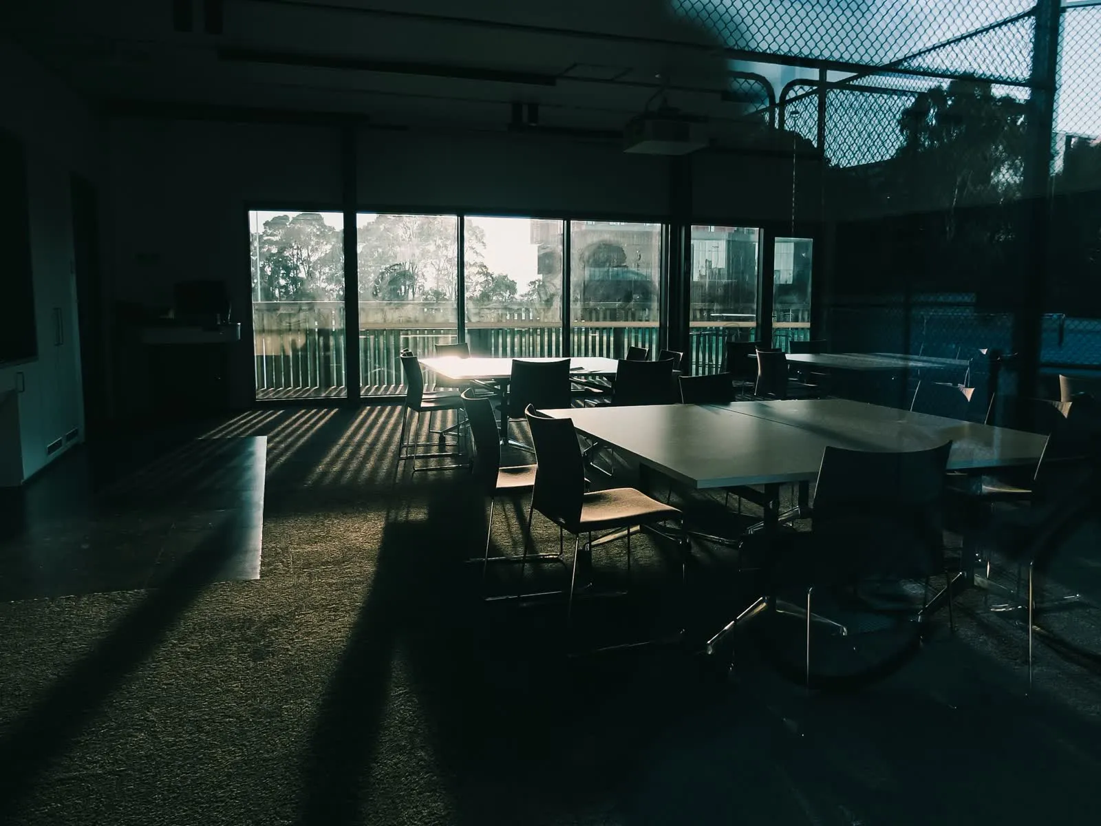An empty meeting room with sunlight falling across the table and chairs.